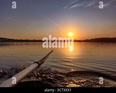Kayak sur le lac au coucher du soleil. Éclaboussure d'eau en kayak. Activité aquatique extérieure. Masurie, Pologne Banque D'Images