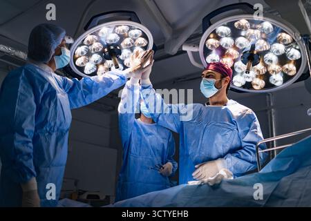 Chirurgiens célébrant en salle d'opération Banque D'Images