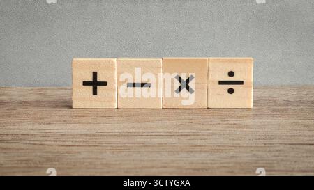 Quatre signes fondamentaux d'opération mathématique sur des blocs de bois : addition, soustraction, multiplication et division pour l'éducation et les concepts d'affaires. Banque D'Images