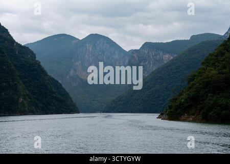Une rivière sereine coule à travers des montagnes verdoyantes sous un ciel nuageux dans la ville de Yichang, en Chine. Banque D'Images