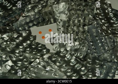 Une pile de plaquettes thermoformées de pilules usées et vides - échantillon de pilules orange au centre - l'utilisation excessive de pilules peut être dangereuse. Banque D'Images