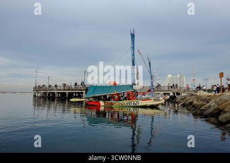 Un bateau traditionnel coloré nommé « Den Bagus » a accosté à Ancol Pier, au nord de Jakarta. Les habitants apprécient le calme front de mer par un après-midi nuageux Banque D'Images