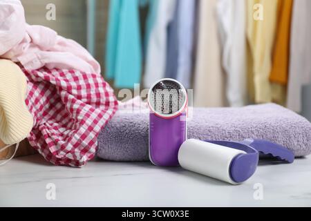 Rouleau à peluches, rasoir en tissu, serviette et vêtements sur table en marbre blanc à l'intérieur Banque D'Images