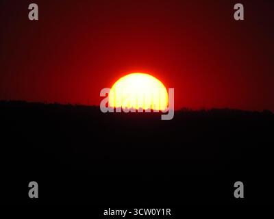 Un coucher de soleil spectaculaire sur le paysage sud-africain, avec de riches teintes orange et rouge illuminant l'horizon et le terrain silhouetté Banque D'Images
