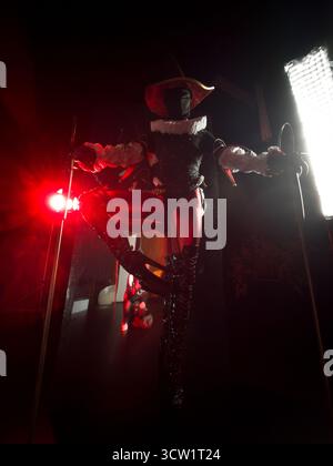 Prise de vue dynamique et en bas angle d'un mystérieux bouffon ou d'un arlequin dans un décor sombre, illuminé de façon spectaculaire par des lumières rouges et blanches intenses. Hallo Banque D'Images