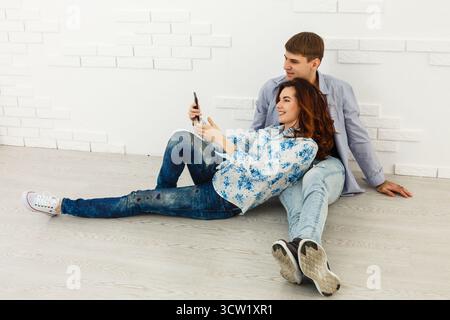 Couple rêveur couché sur le sol dans une pièce vide et regardant vers le haut, imaginez le futur projet de design d'intérieur, fond blanc. Banque D'Images