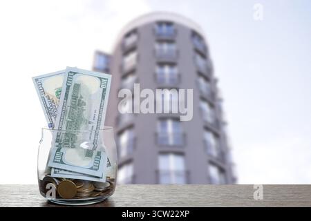Pot avec des dollars et des pièces contre condominium. Économiser de l'argent pour acheter appartement Banque D'Images