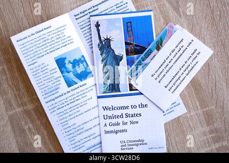 Carte verte de résident permanent dans l'enveloppe et le guide pour les nouveaux immigrants se trouve sur la table en bois de près Banque D'Images