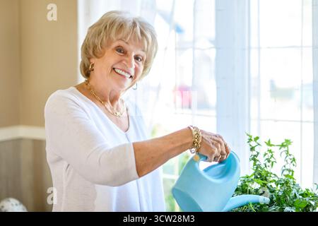 Une femme mature qui s'occupe de fleurs en pot à la maison Banque D'Images