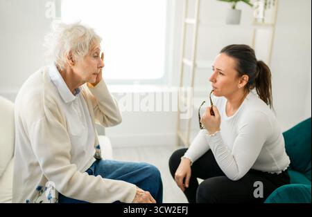 Une vieille femme pensant avec le psychologue dans le bureau de consultation pour l'esprit, l'évaluation ou l'évaluation. Banque D'Images