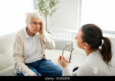 Une vieille femme pensant avec le psychologue dans le bureau de consultation pour l'esprit, l'évaluation ou l'évaluation. Banque D'Images