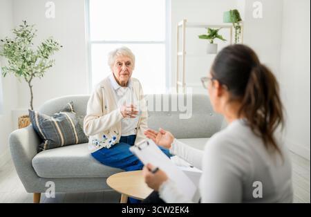 Une vieille femme pensant avec le psychologue dans le bureau de consultation pour l'esprit, l'évaluation ou l'évaluation. Banque D'Images