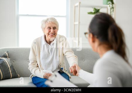 Une vieille femme pensant avec le psychologue dans le bureau de consultation pour l'esprit, l'évaluation ou l'évaluation. Banque D'Images