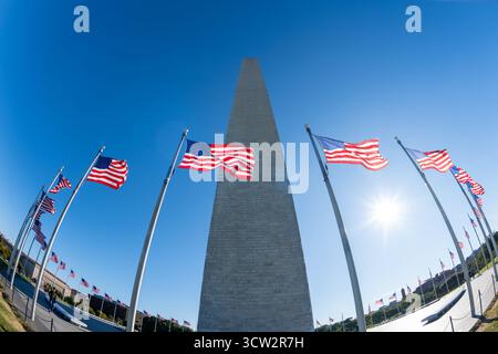 Washington Monument avec drapeaux américains Washington DC // WASHINGTON DC — le Washington Monument, honorant George Washington, le premier président américain, est mis en vedette avec de nombreux drapeaux américains qui flottent autour de sa base. Cet obélisque emblématique est la plus haute structure en pierre et obélisque du monde, mesurant 169,046 mètres (554 pieds 7+11/32 pouces) de haut. Situé sur le National Mall, c'est un point de repère clé dans la capitale nationale. Un anneau de 50 drapeaux américains, représentant les états américains, entoure le monument. C'est un symbole puissant de l'histoire américaine et de la fierté nationale. Banque D'Images