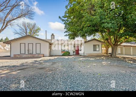 Une charmante maison blanche avec une porte rouge vibrante avec une allée de gravier menant gracieusement à son entrée en face de lui Banque D'Images