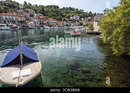 Charmante scène portuaire méditerranéenne avec des maisons en pierre le long de l'eau, de petits bateaux, et turquoise, eau claire créant une atmosphère balnéaire tranquille Banque D'Images