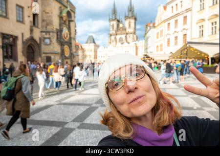 Prague, République tchèque, 7 août 2023. Une femme d'âge mûr prend un selfie sur la place emblématique et bondée de la vieille ville. Arrière-plan flou, destination de voyage Banque D'Images