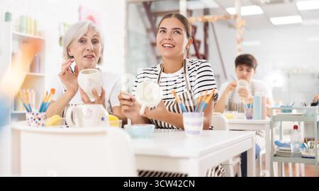 Gaies vieilles et jeunes tasses de peinture wowen dans la masterclass de poterie Banque D'Images