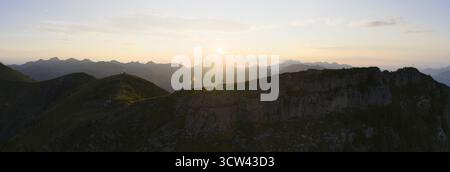 Vue aérienne du soleil projetant une lueur dorée sur les pics accidentés de la dent de Valerette, Monthey, Valais, Suisse. Banque D'Images