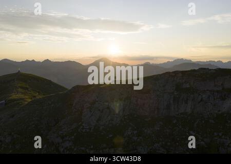 Vue aérienne d'une figure solitaire debout au sommet de la dent de Valerette accidentée, baignée dans la lueur chaude du soleil couchant, Monthey, Valais, Suisse. Banque D'Images
