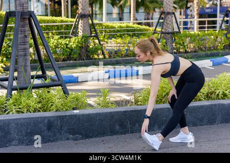 Entraînement jeune femme exercice de sport, FIT femme effectue l'étirement des jambes en plein air, préparant le corps pour Banque D'Images