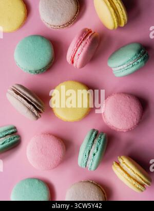Vue de dessus gros plan de macarons colorés sur fond rose. Banque D'Images