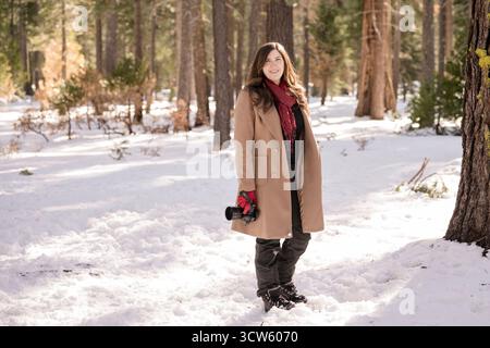 Femme marchant dans la neige tenant un appareil photo Banque D'Images