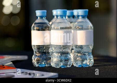Un groupe de petites bouteilles en plastique avec de l'eau potable propre et des étiquettes blanches vierges Banque D'Images