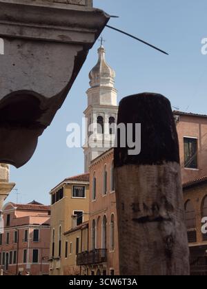 Vue rapprochée du Campanile vénitien à travers les piliers - Un Campanile vénitien s'élève au-dessus des bâtiments colorés, encadré au premier plan par un W. Banque D'Images