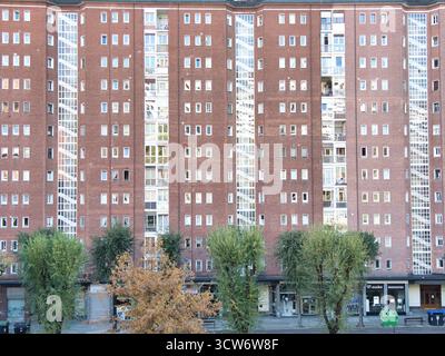 Façade de bâtiment d'appartement en brique rouge symétrique - vue frontale complète d'un grand immeuble résidentiel avec un motif répétitif de briques rouges a Banque D'Images