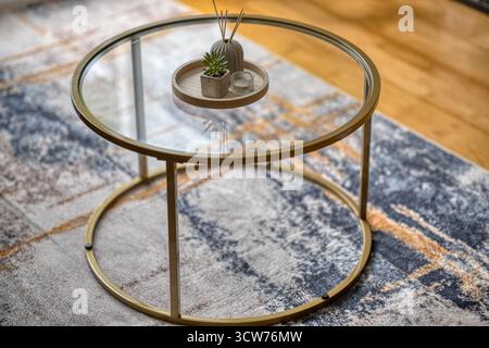 Élégante table basse en verre avec cadre doré et éléments décoratifs dans un cadre intérieur confortable Banque D'Images