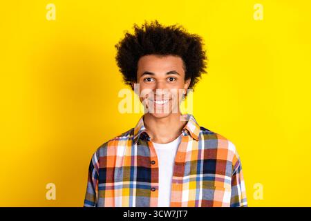 Portrait d'un jeune homme souriant brillamment sur un fond jaune vif portant une chemise à carreaux élégante Banque D'Images