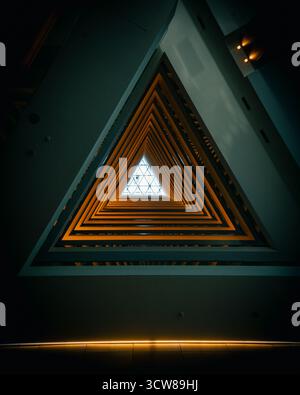 Vue architecturale abstraite regardant vers le plafond de l'hôtel ICON, avec un motif géométrique en forme de bouton de jeu avec des tons orange et bleu. Banque D'Images