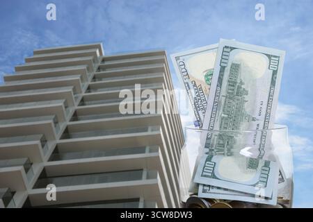 Pot avec des dollars et des pièces contre condominium. Économiser de l'argent pour acheter appartement Banque D'Images