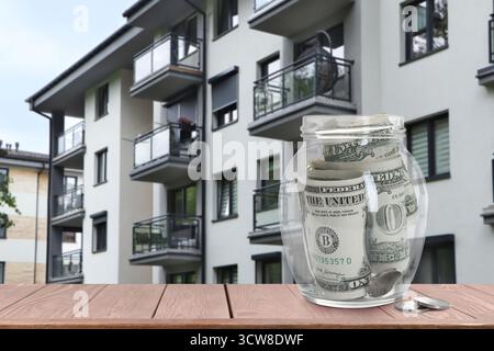 Pot avec des dollars et des pièces contre condominium. Économiser de l'argent pour acheter appartement Banque D'Images