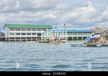 PHUKET, THAÏLANDE - 12 NOVEMBRE 2017 : scène de village côtier avec des bâtiments étanches et des bateaux de pêche par une journée nuageuse. Banque D'Images