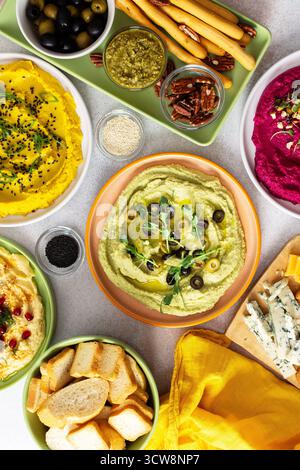 Une planche de charcuterie vibrante présente du brocoli, du curcuma, du houmous classique et de la betterave, associés à des olives, craquelins, et garnitures fraîches, parfait pour Banque D'Images