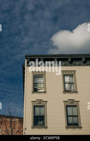 Un charmant bâtiment historique présente des détails architecturaux complexes sous un ciel bleu vif avec des nuages. Banque D'Images