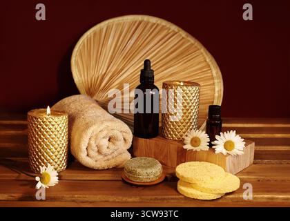 Still life of spa accessories with rolled towels, natural soaps, oils and candles on wooden surface. Warm lighting highlighting textures and neutral Banque D'Images