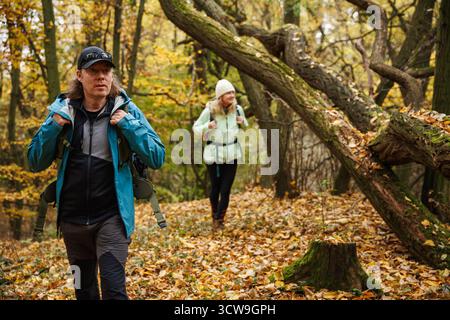 Randonnée dans la forêt d'automne. Deux amis portant des vêtements de sport marchant sur le sentier de trekking dans les bois Banque D'Images