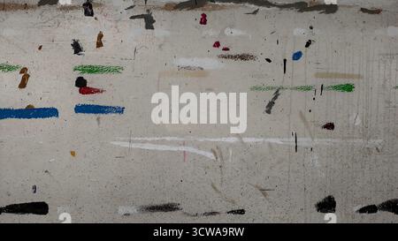 Rue ou mur urbain texturé fortement recouvert d'éclaboussures et de stries de peinture abstraites sales. Fond gris avec des lignes multicolores Banque D'Images