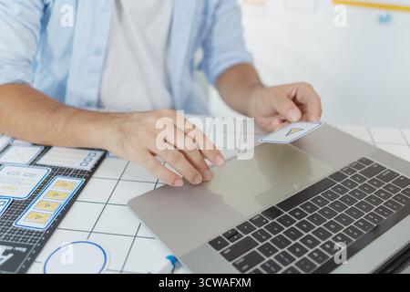 Un concepteur masculin s'est concentré sur les tâches d'interface utilisateur UX, créant des prototypes d'applications avec des éléments filaires, des esquisses et des palettes de couleurs. Il travaille avec des idées créatives pour optimiser Banque D'Images