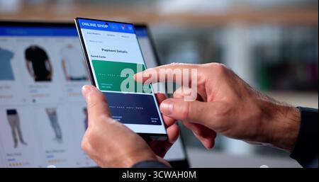 Homme senior achetant des chaussures en ligne à l'aide d'un smartphone dans son salon. Banque D'Images