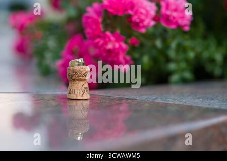 anneaux de mariage en or des jeunes mariés sur un bouchon de champagne et des fleurs Banque D'Images