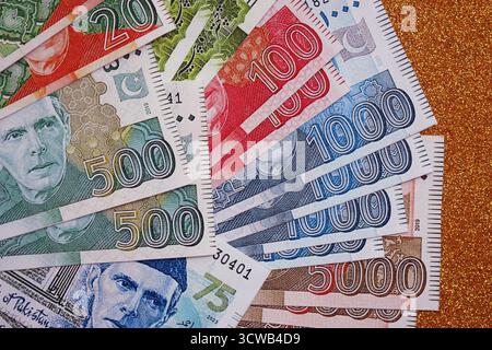 Pakistan roupies billets de banque sur fond jaune doré. Les factures d'argent pakistanaises actuelles sont sur la table en gros montant. Le concept d'affaires et d'investissement au Pakistan Banque D'Images
