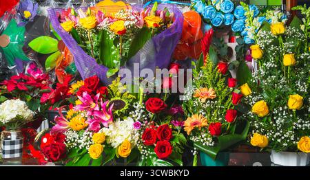 Collection vibrante d'arrangements floraux mixtes, y compris des roses, des lis, des tournesols et des gerberas dans une exposition de marché. Banque D'Images