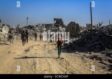 Khan Yunis, Territoires palestiniens. 11 octobre 2025. Les gens marchent à travers les ruines de Khan Younis, alors que les Palestiniens déplacés rentrent chez eux après le retrait de l’armée israélienne et l’entrée en vigueur du cessez-le-feu. Crédit : Abed Rahim Khatib/dpa/Alamy Live News Banque D'Images