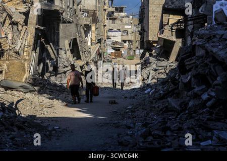 Khan Yunis, Territoires palestiniens. 11 octobre 2025. Les gens marchent à travers les ruines de Khan Younis, alors que les Palestiniens déplacés rentrent chez eux après le retrait de l’armée israélienne et l’entrée en vigueur du cessez-le-feu. Crédit : Abed Rahim Khatib/dpa/Alamy Live News Banque D'Images