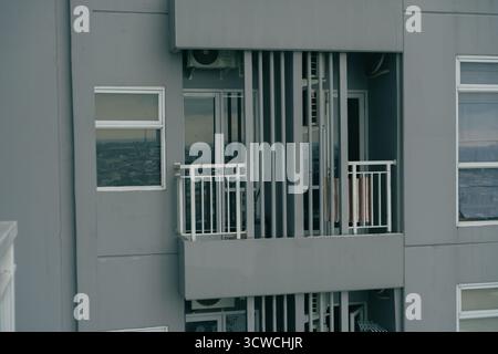 Vue extérieure d'un immeuble moderne d'appartements gris avec balcons et fenêtres donnant sur un paysage urbain Banque D'Images