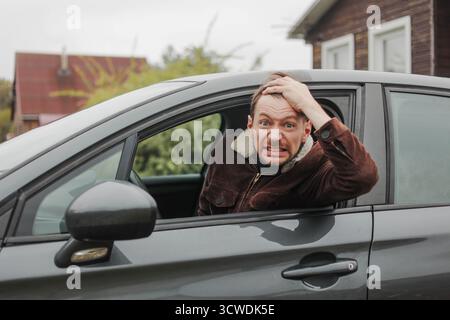Portrait d'un jeune homme choqué assis dans sa voiture, regardant la caméra. Banque D'Images